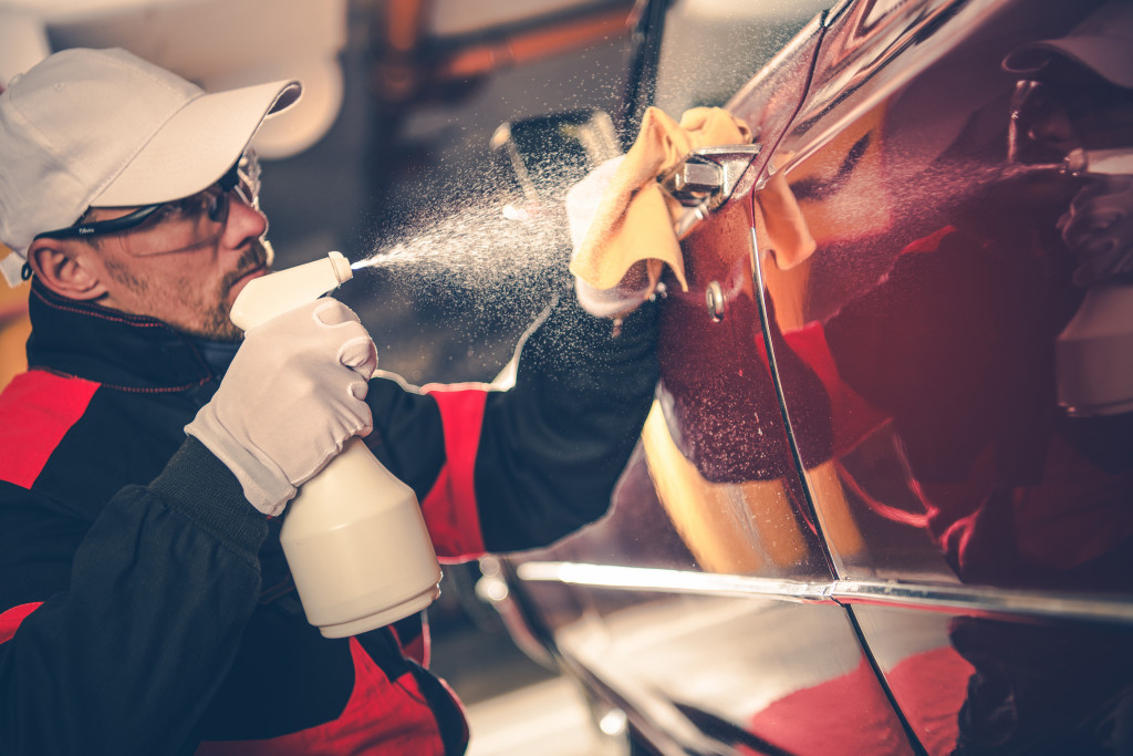 A professional washing a red car while wearing gear