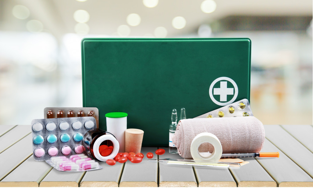 A first aid kit with bandages, tapes, and medicine on a wood table