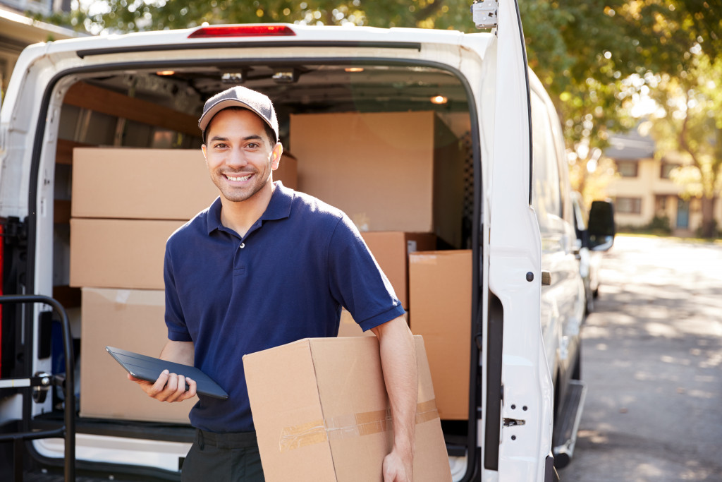 Employee carries box from open van