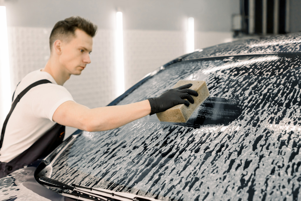 a man cleaning a car with sponge