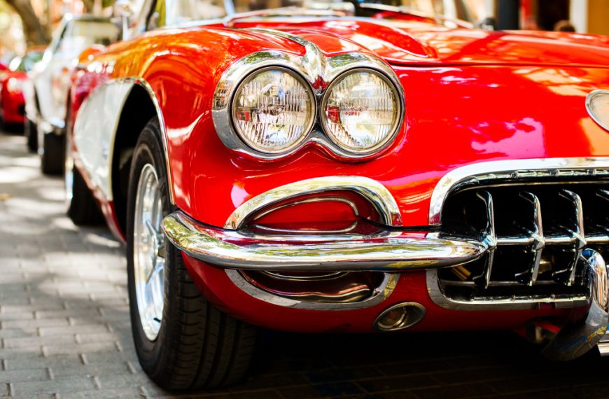 closeup of a red vintage car's bumper area outdoors