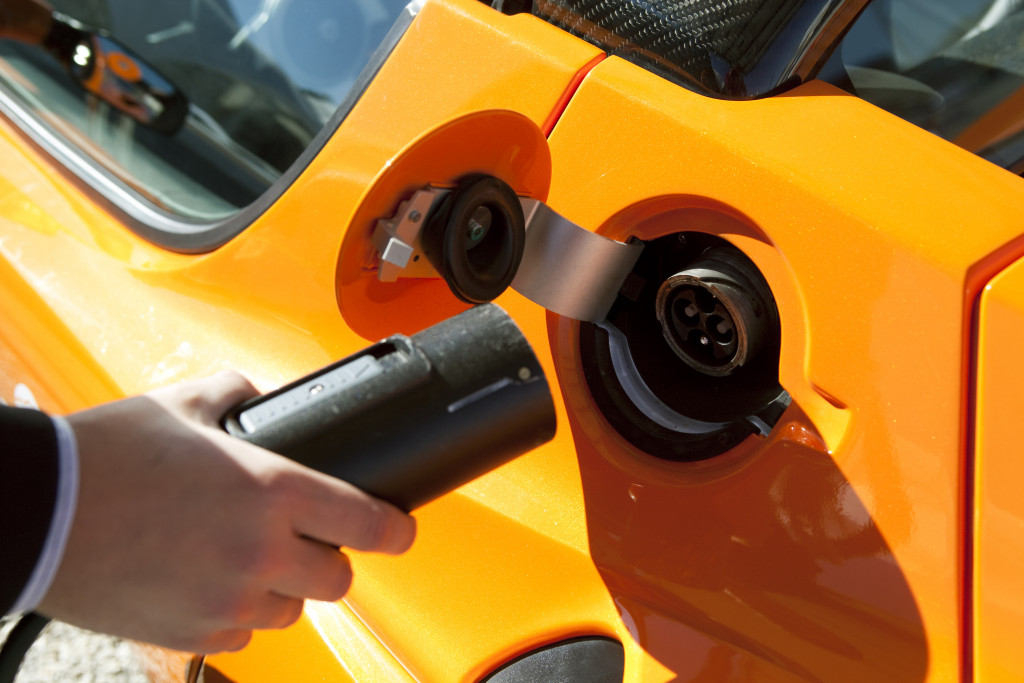 hand charging orange electric car