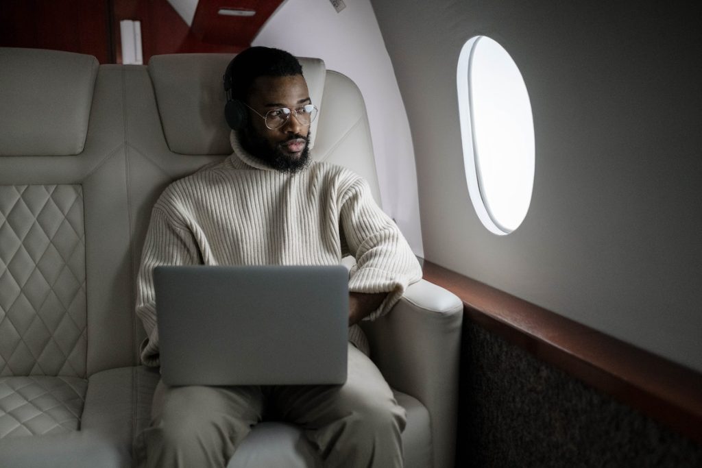 Man in White Sweater Sitting on Couch Using Macbook