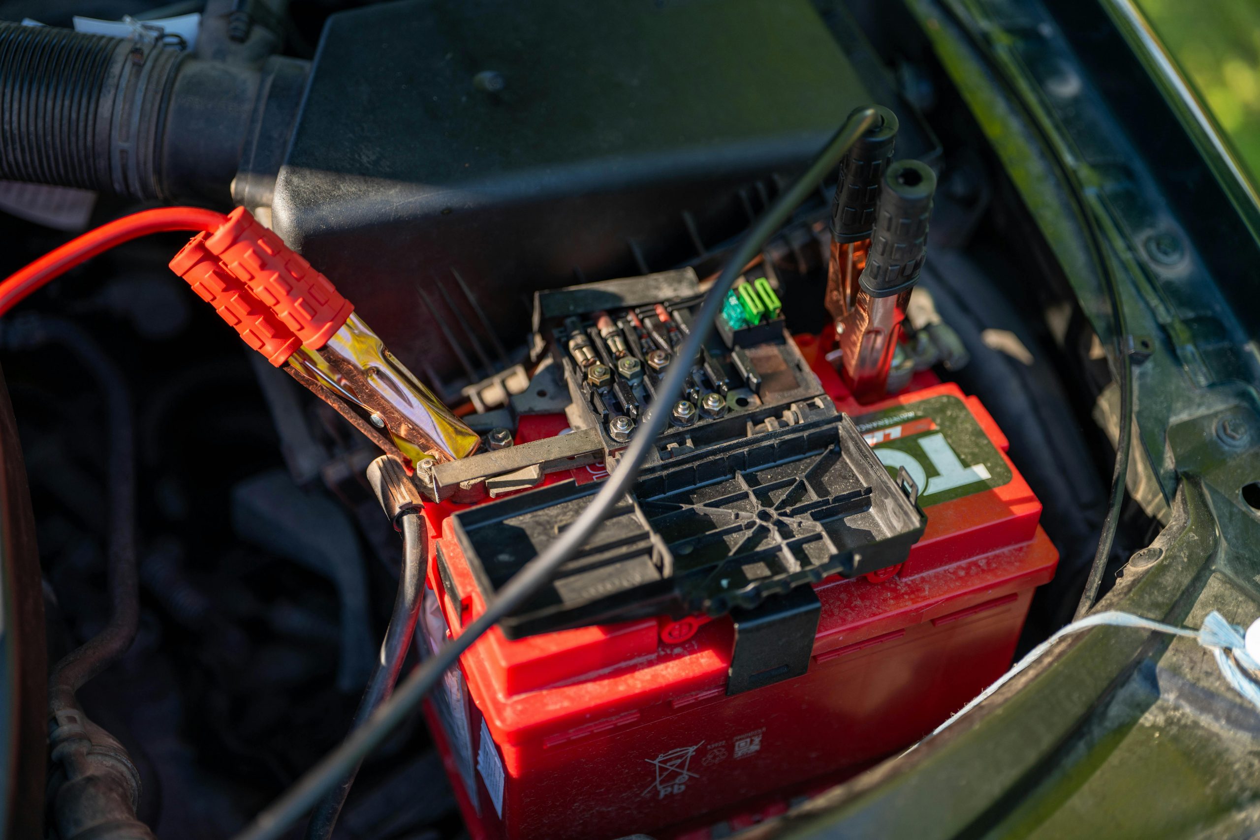 jumper cable clamps attached to a dead battery